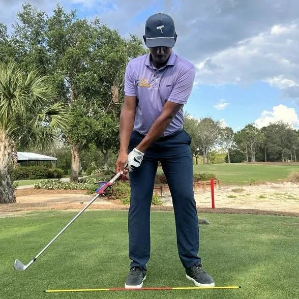 Plastic golf swing plane simulator trainer on a practice mat.