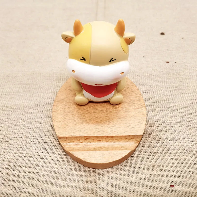 Solid beech wood phone stand with a decorative resin puppy figurine, holding a mobile phone at an angle with a charging cable threaded through the back.