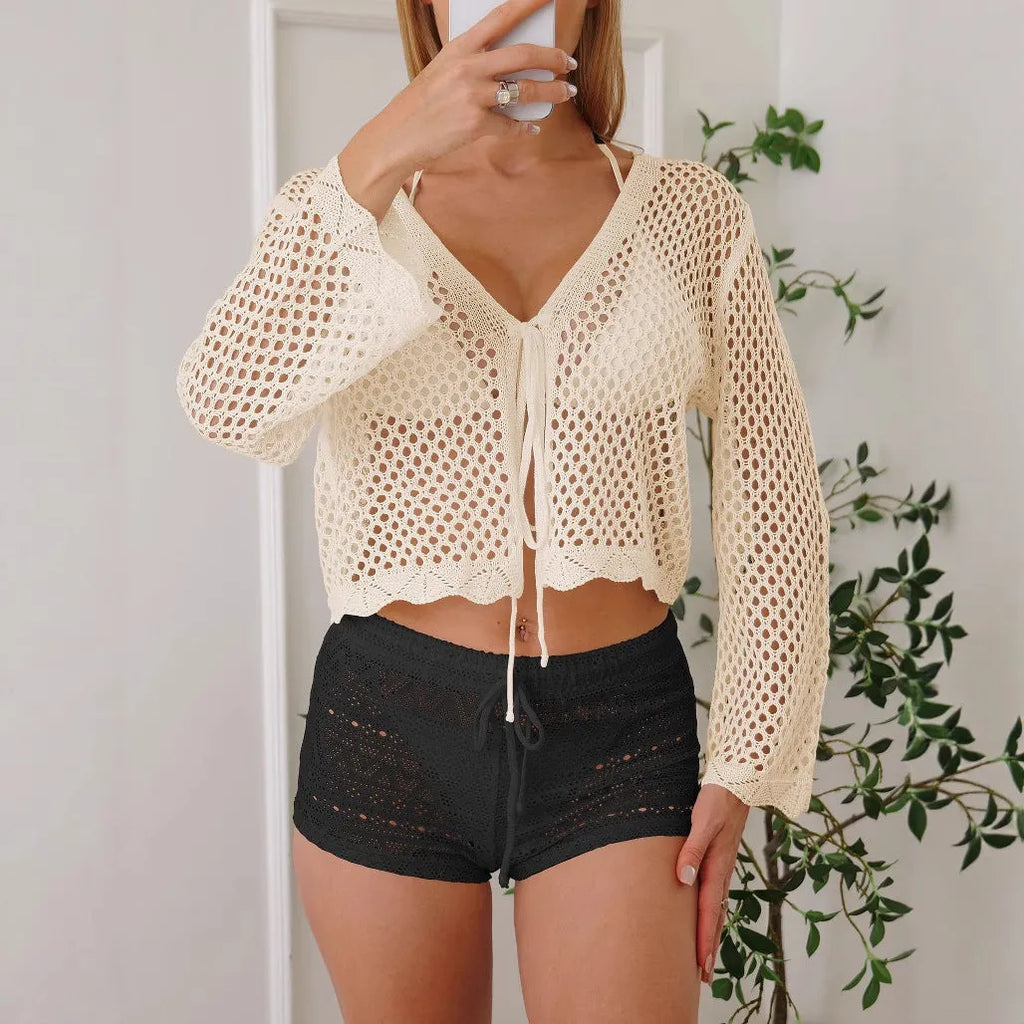 Short apricot hollow woven cardigan blouse with bell sleeves on a hanger.