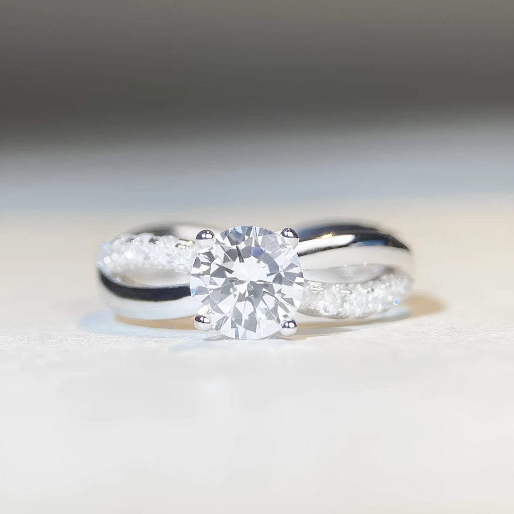 Silver ring with 1 karat moissanite in four-claw setting on a geometric twisted arm band.