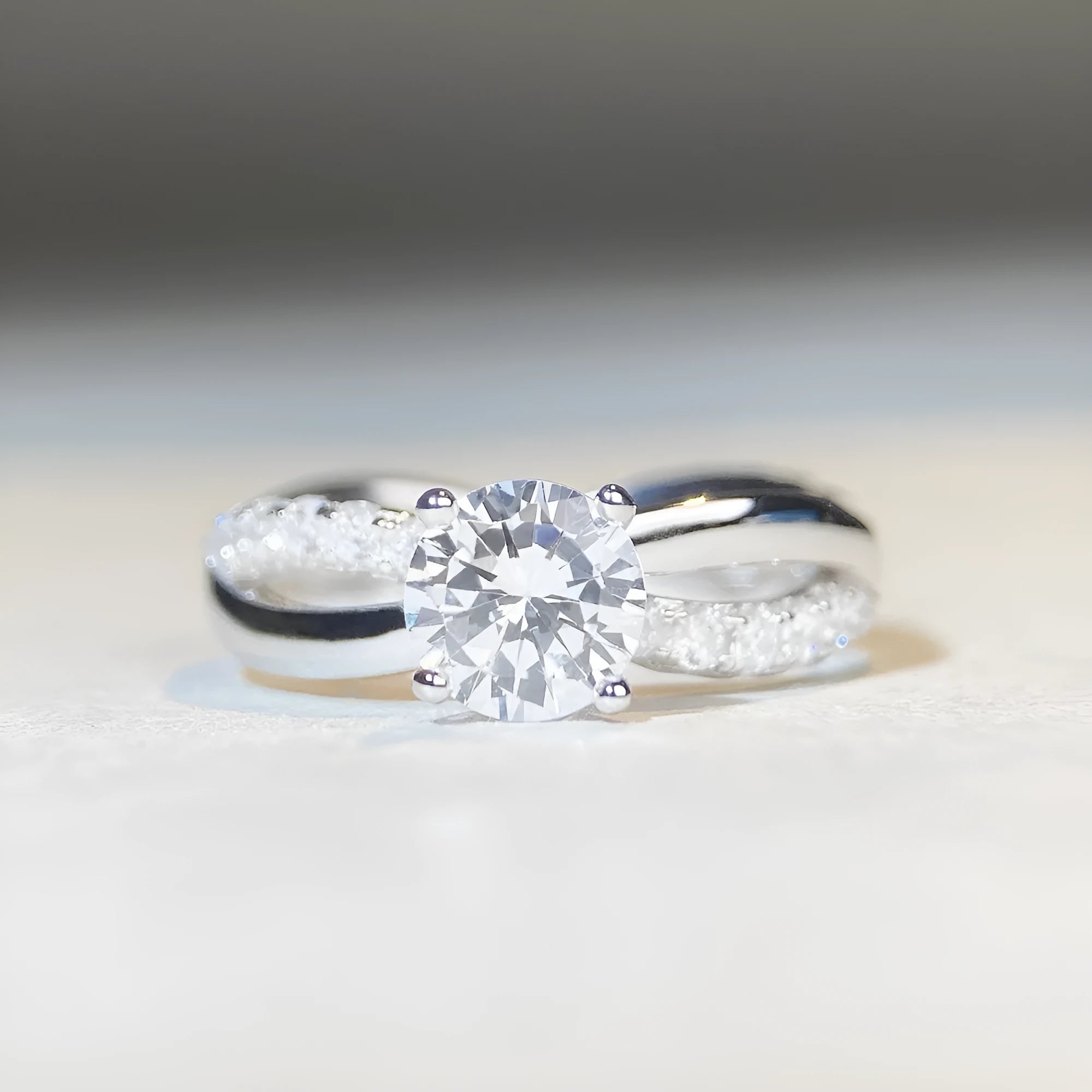 Silver ring with 1 karat moissanite in four-claw setting on a geometric twisted arm band.