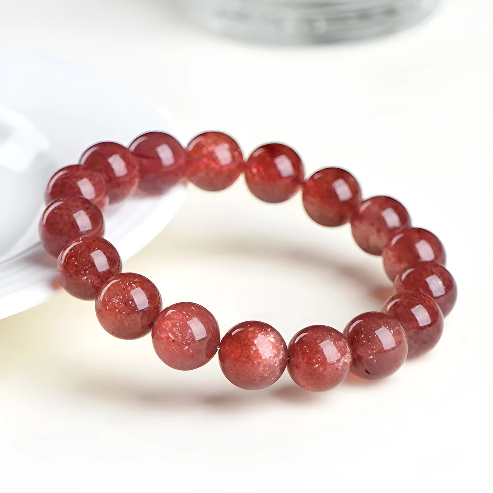 Geometric bead strawberry quartz bracelet in Starlight colour on a wrist, showing size options.