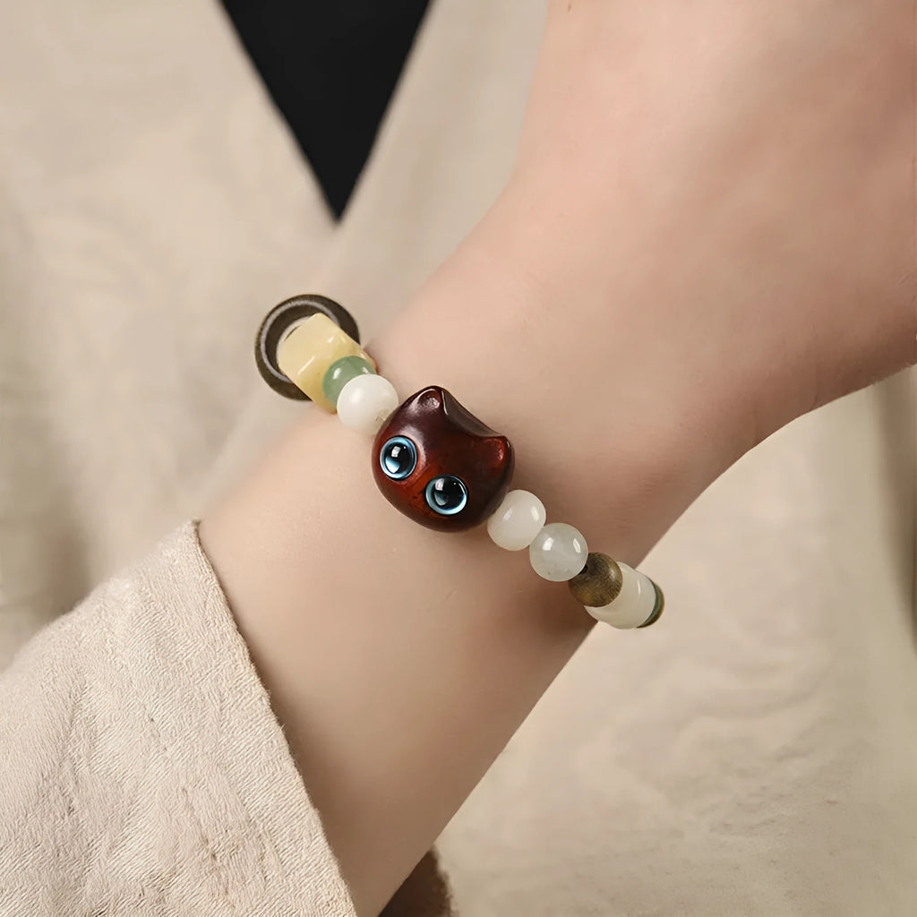 Hand-woven beaded bracelet with bodhi, jade, and ebony beads featuring a cartoon cat's paw charm.