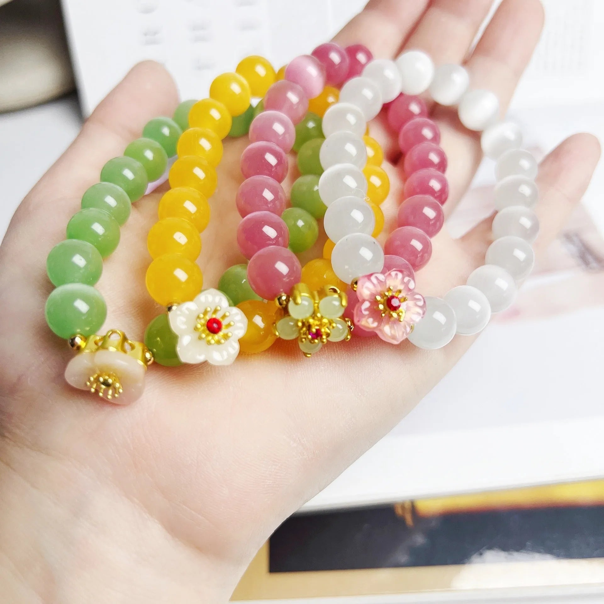 Handmade glass bead bracelet with floral design in green, pink, white, or yellow.