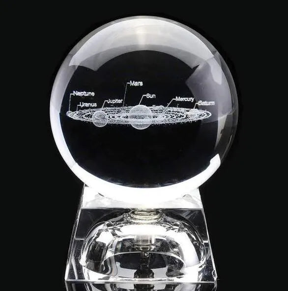 Solar system laser-engraved inside K9 crystal ball on a wooden desk beside an LED base