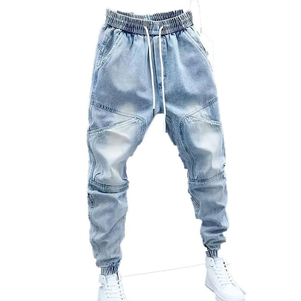 Men's light blue micro-elastic cotton denim pencil trousers with drawstring waist and elastic ankle bands on a model.