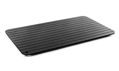 Black aluminium fast defrosting tray with silica gel feet on a kitchen countertop.