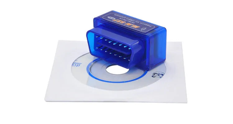 Small black ELM327 OBD2 Bluetooth diagnostic scanner next to a vehicle's OBD2 port.
