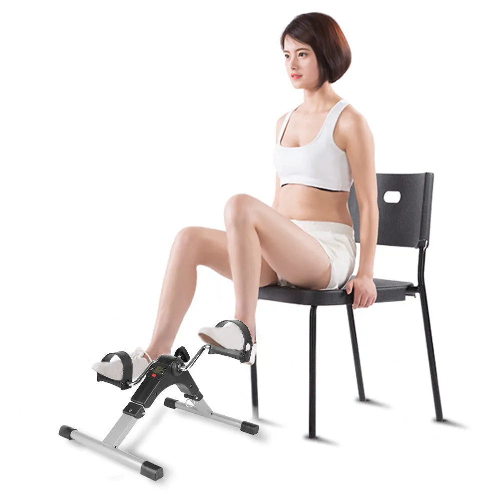 Silver and black exercise mini spinning bike on hard floor with pedals and non-slip foot pads