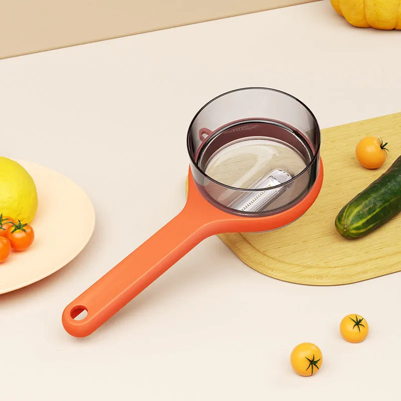 Light green kitchen peeler with a small orange storage bucket attached underneath the blade.