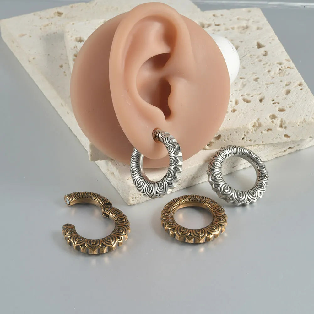 Pair of large antique silver dragon-shaped geometric ear cuffs with hollow-out detail on a plain background.