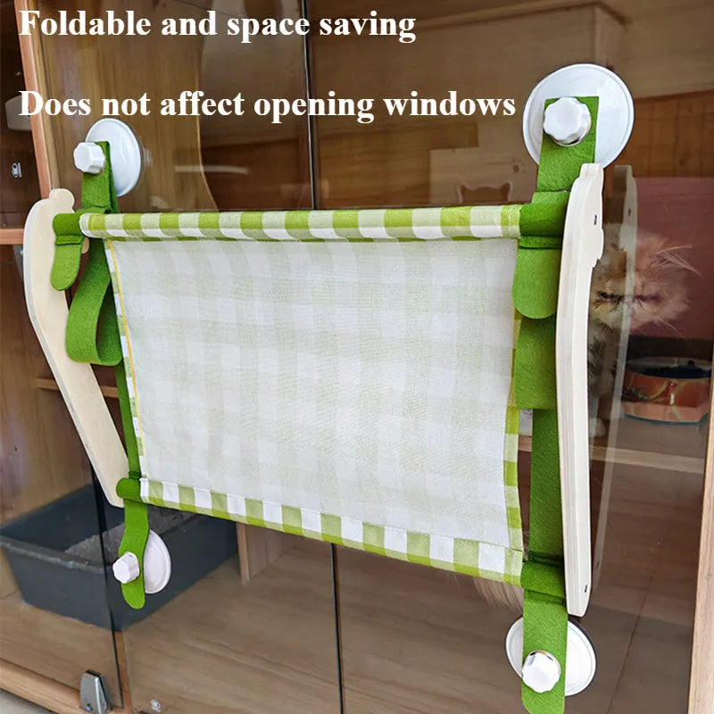 Green wooden cat window hammock with suction cups attached to glass, showing a removable linen mat.