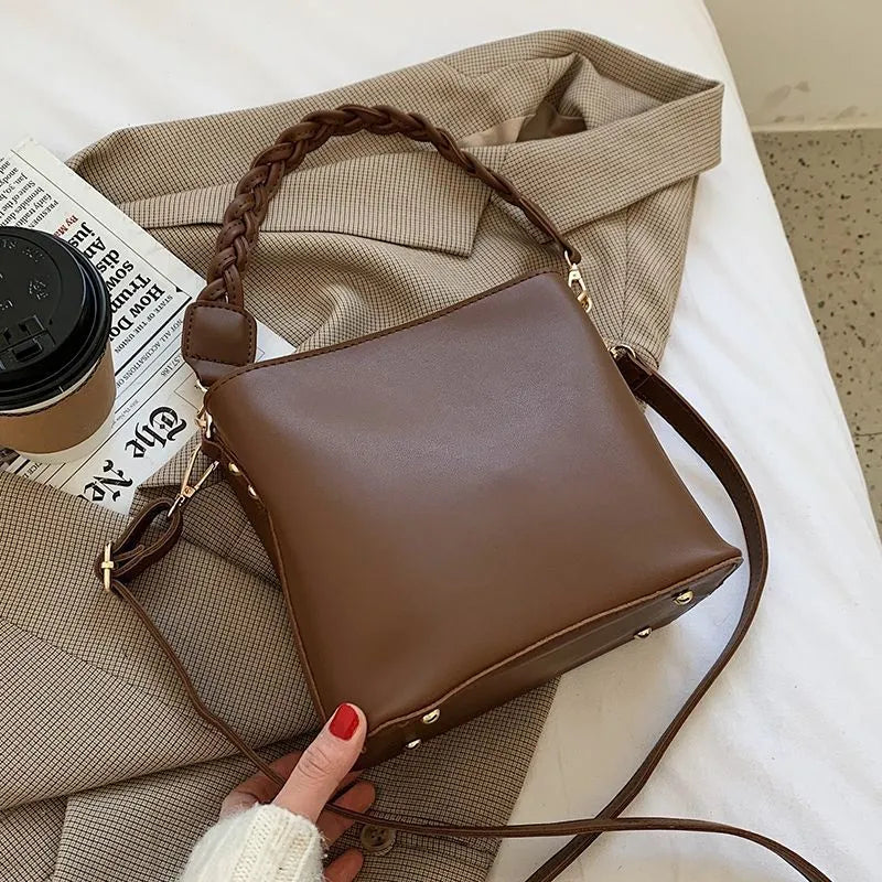 Woven pattern PU leather crossbody bucket bag worn underarm, shown in khaki colour.