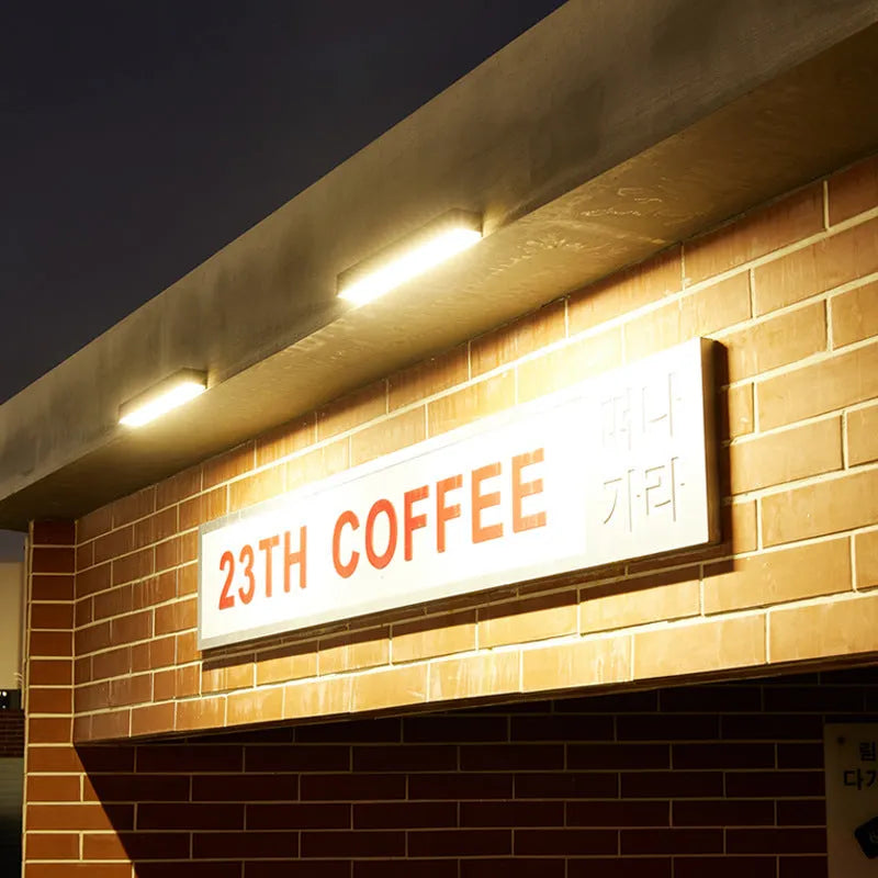 Black solar-powered outdoor wall lamp with integrated solar panel and LED light.