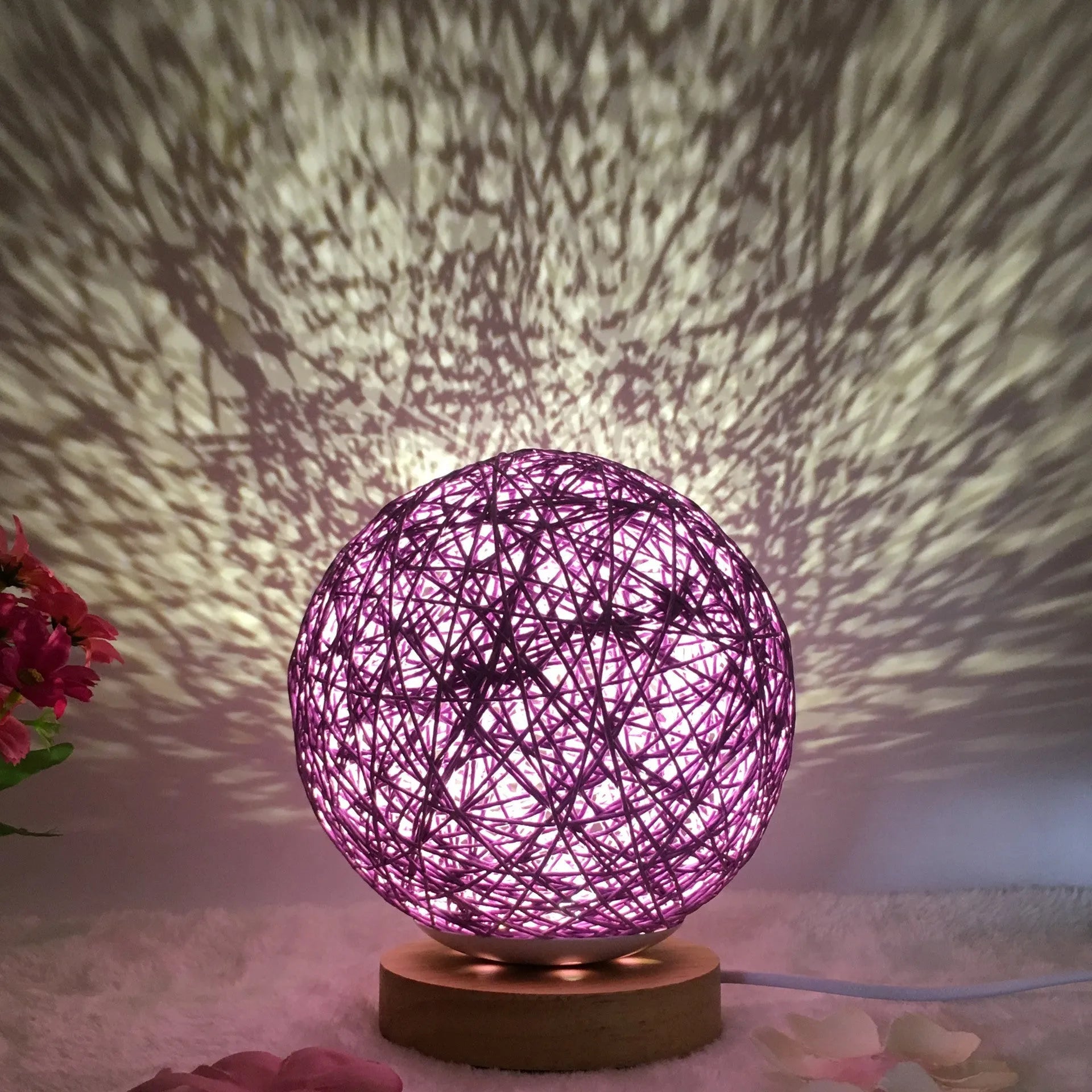 Rattan ball table lamp with woven shade and warm LED lighting on wooden surface