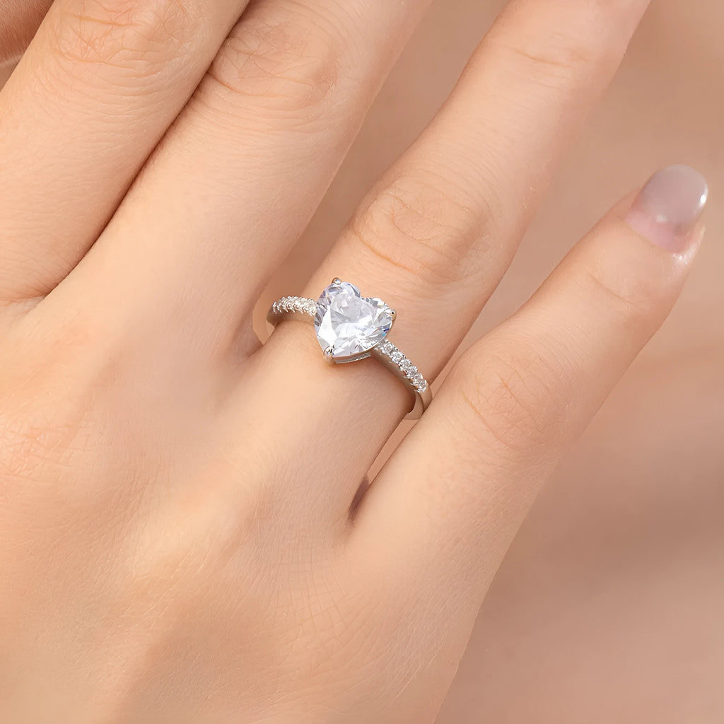 Women's sterling silver love ring with heart zircon mosaic in white color, side view on white background