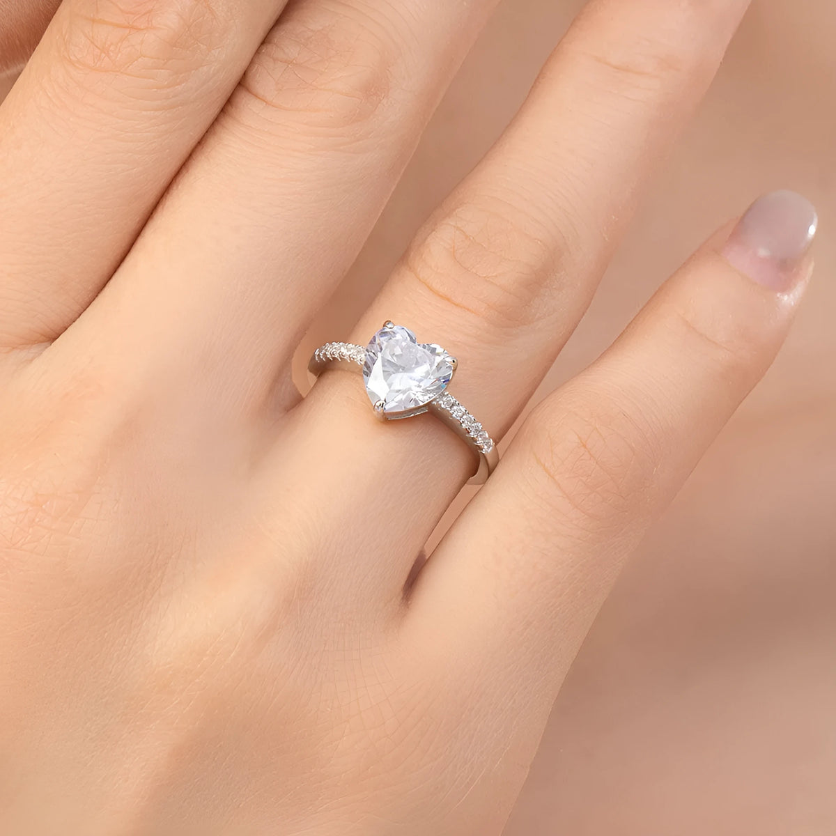 Women's sterling silver love ring with heart zircon mosaic in white color, side view on white background