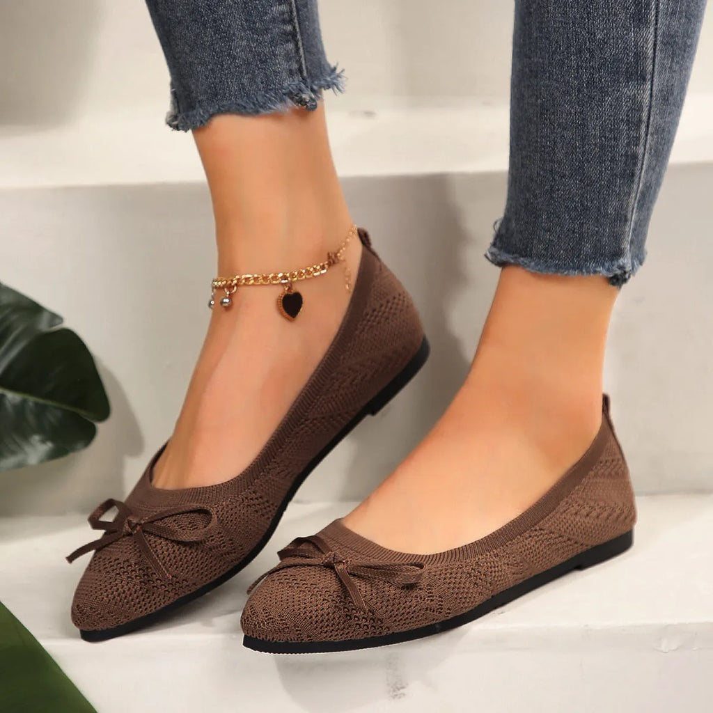 Women's blue knitted flat loafer with bow detail on pointed toe, showing rubber sole