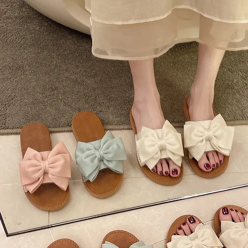 Women's slip-on suede sandals with bow detail in beige, light green, and pink colour options