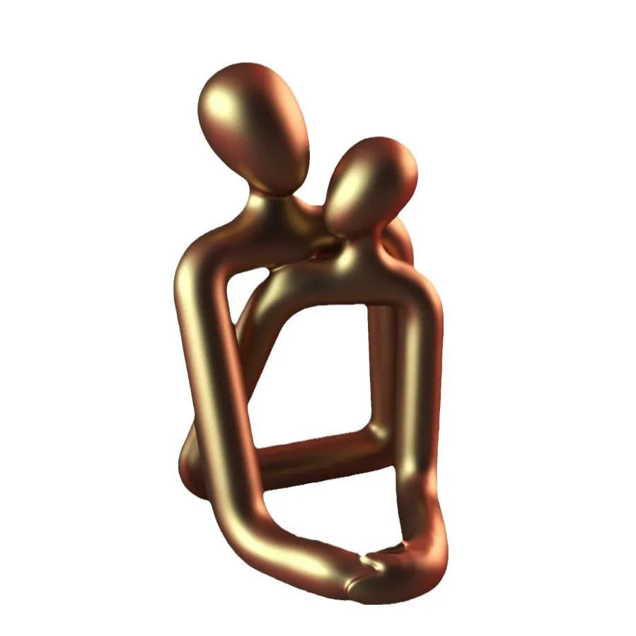 Modern loving couple resin statue in milky white or gold colour on a wooden desk.