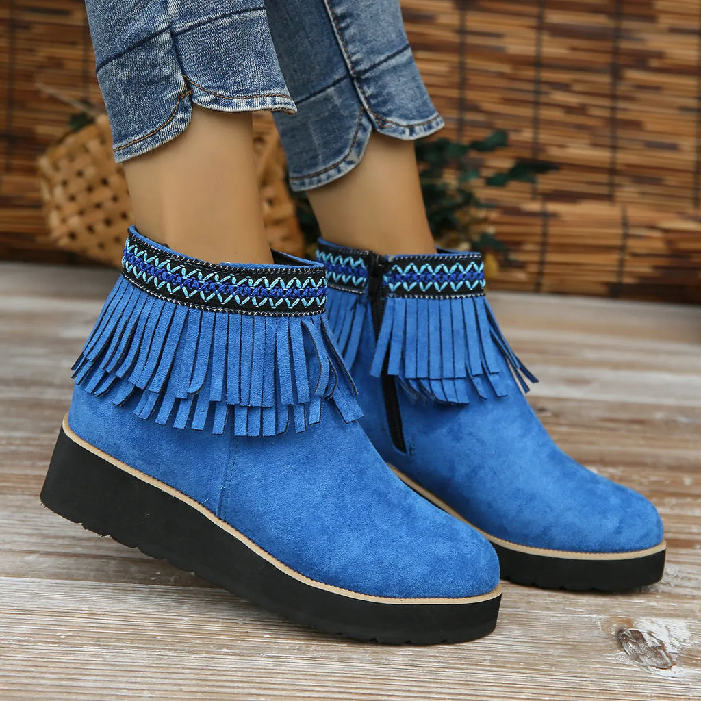 Women's black wedge bootie with suede upper, thick rubber sole, side zipper, and tassel detail.