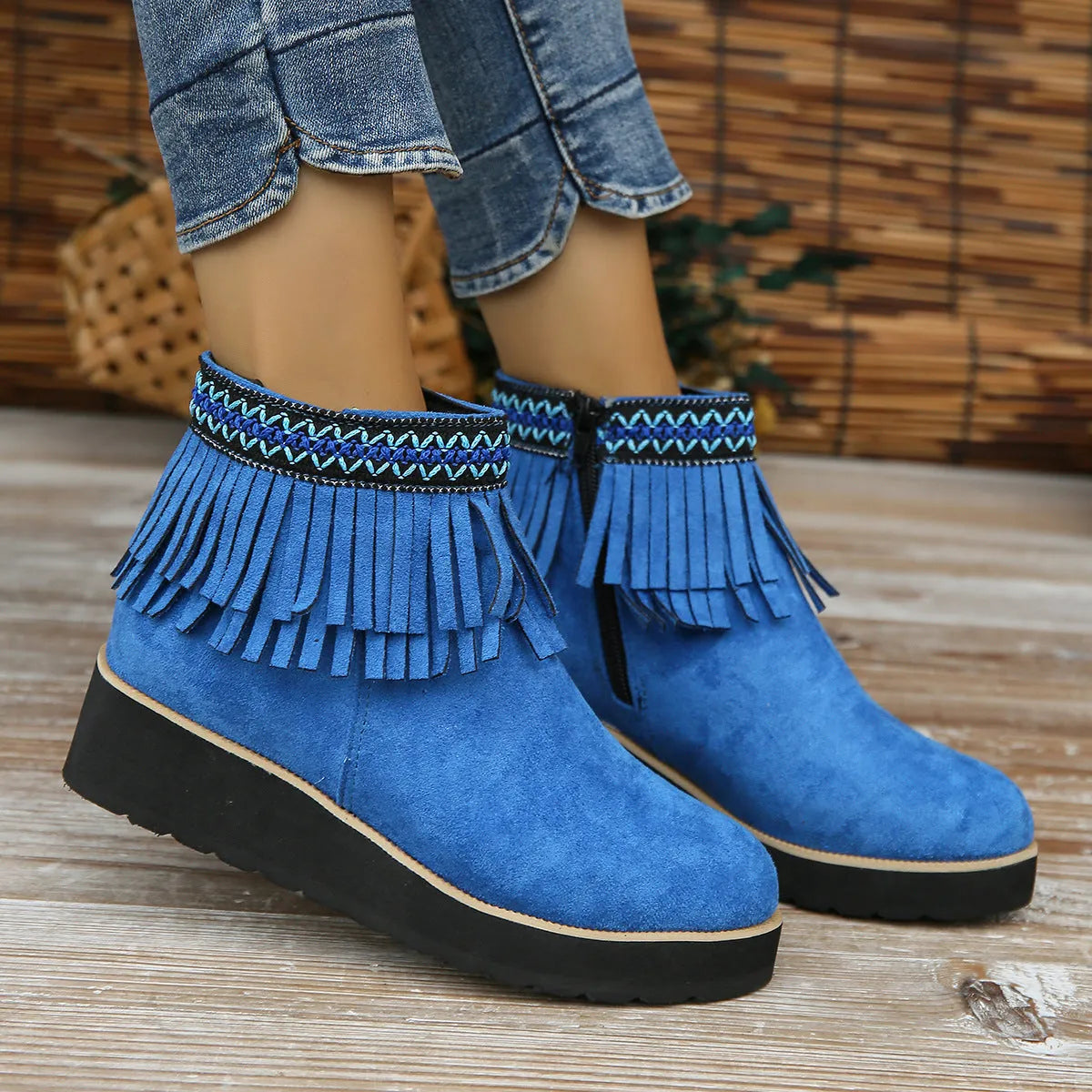Women's black wedge bootie with suede upper, thick rubber sole, side zipper, and tassel detail.