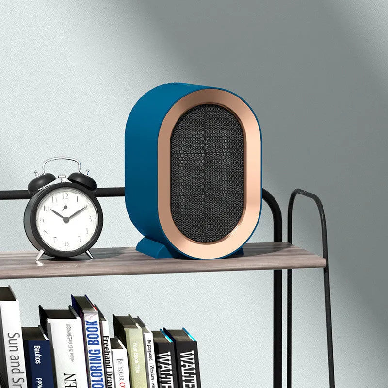 Compact black desktop electric fan heater with mechanical control knobs on a wooden desk.