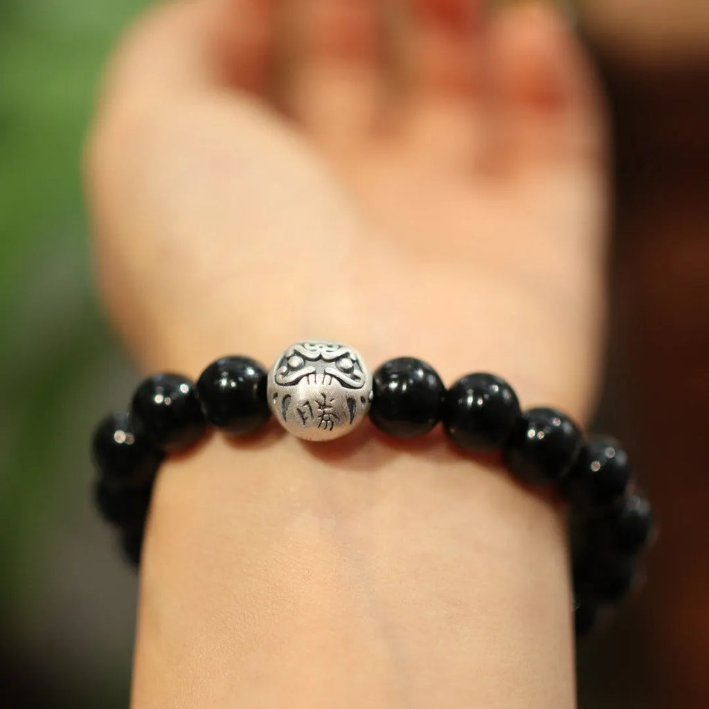Close-up of a black bracelet with 10mm agate beads and sterling silver details on a wrist.