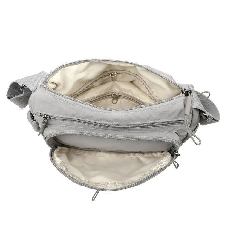 Soft nylon crossbody bag in black, grey, or red with a single shoulder strap and water-repellent finish.