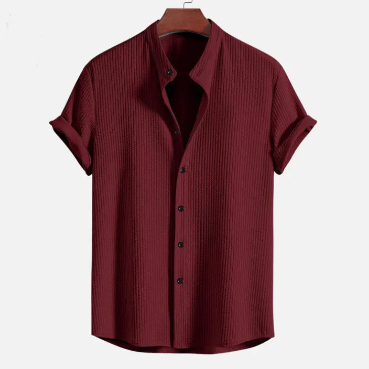 A man wearing a loose-fitting short sleeve casual shirt in a solid colour.