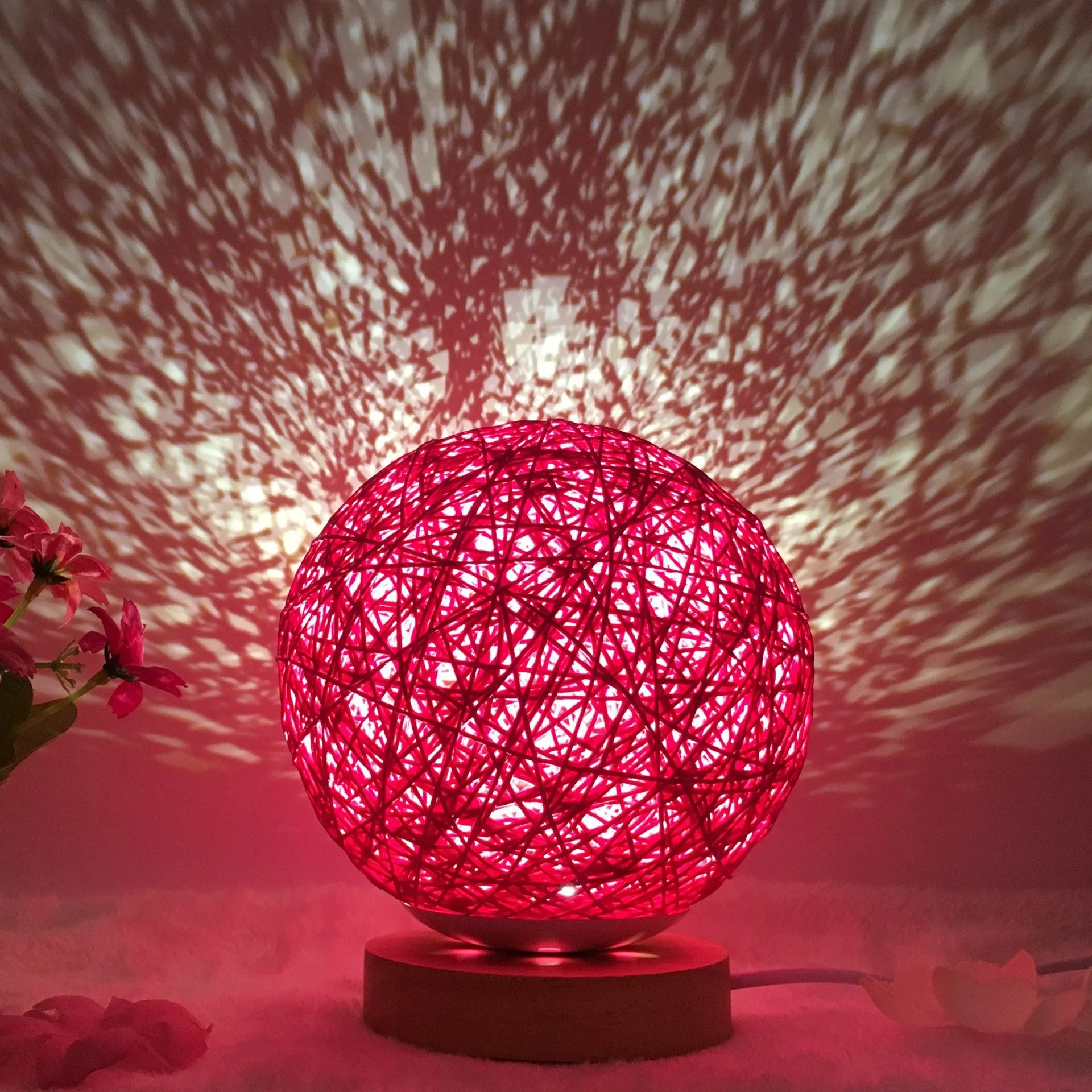 Rattan ball table lamp with woven shade and warm LED lighting on wooden surface