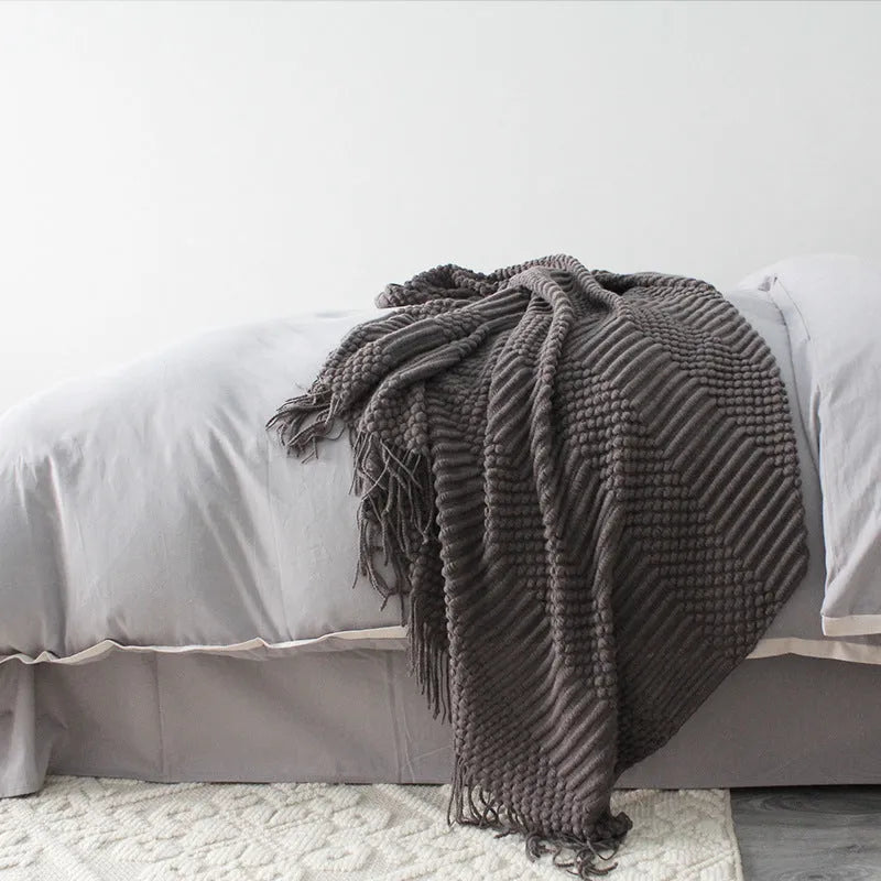 Small grey polyester nap blanket measuring 127 by 170 centimetres folded on a sofa.