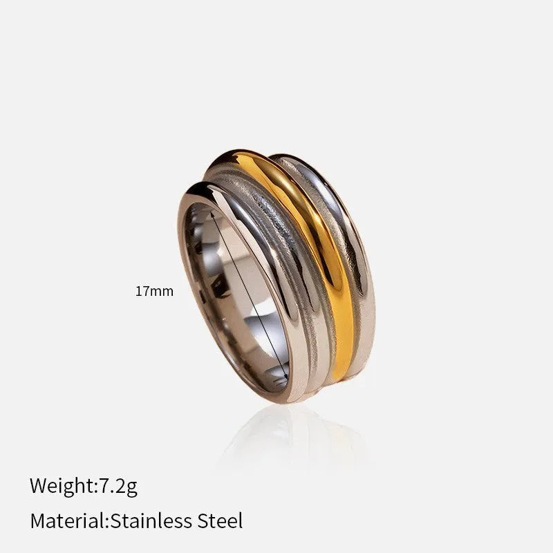 Gold and silver two-tone geometric cross stainless steel ring on a light background showing texture and electroplated finish