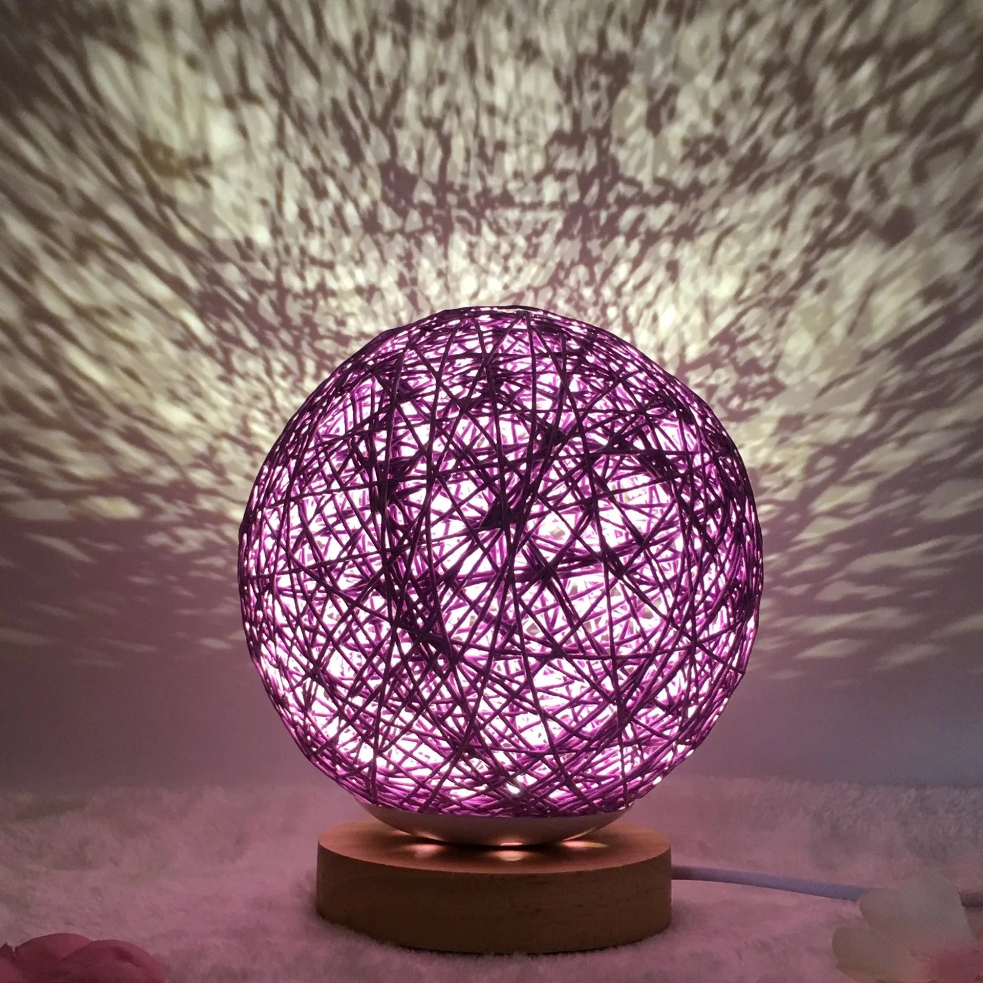 Rattan ball table lamp with woven shade and warm LED lighting on wooden surface