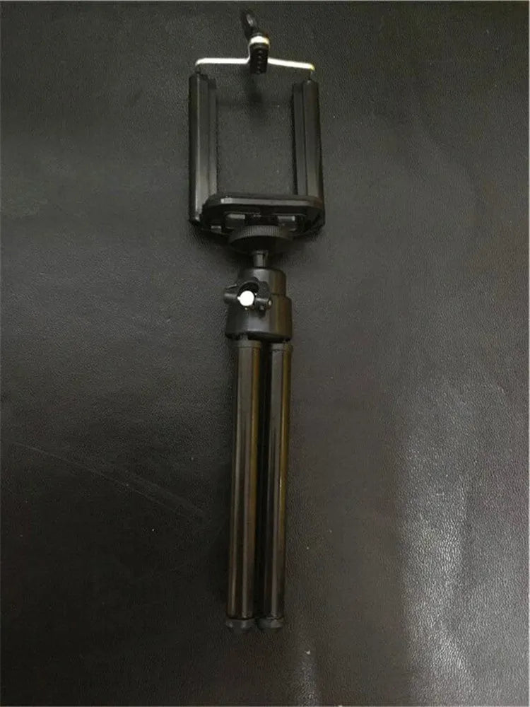 A black or silver desktop phone holder with a two-section adjustable bracket on a wooden desk.