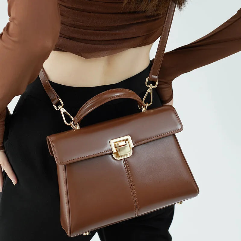 Black genuine leather women's shoulder bag with a clasp closure and long adjustable strap.