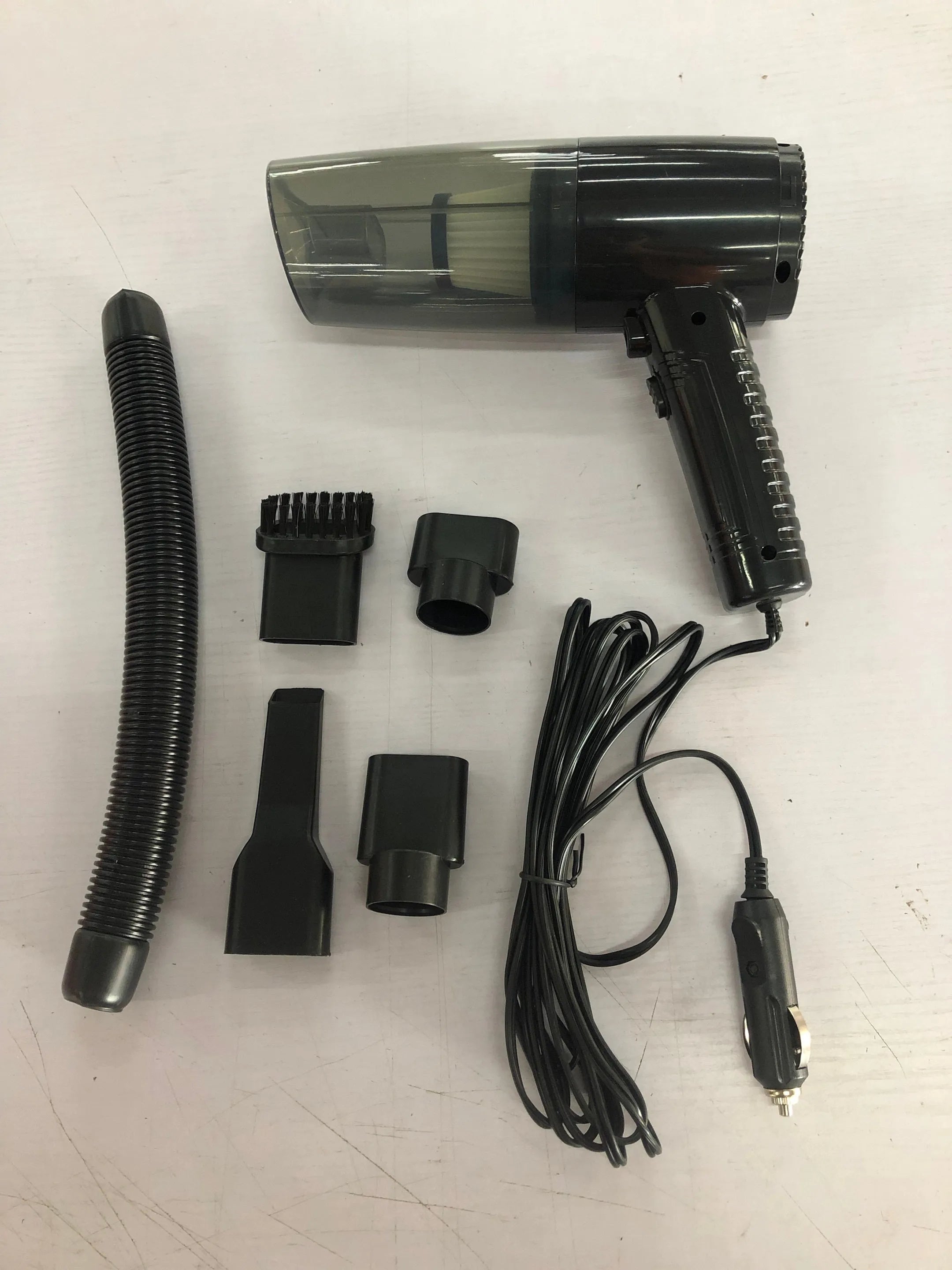 Handheld black car vacuum cleaner with attachments and long cord on a car seat