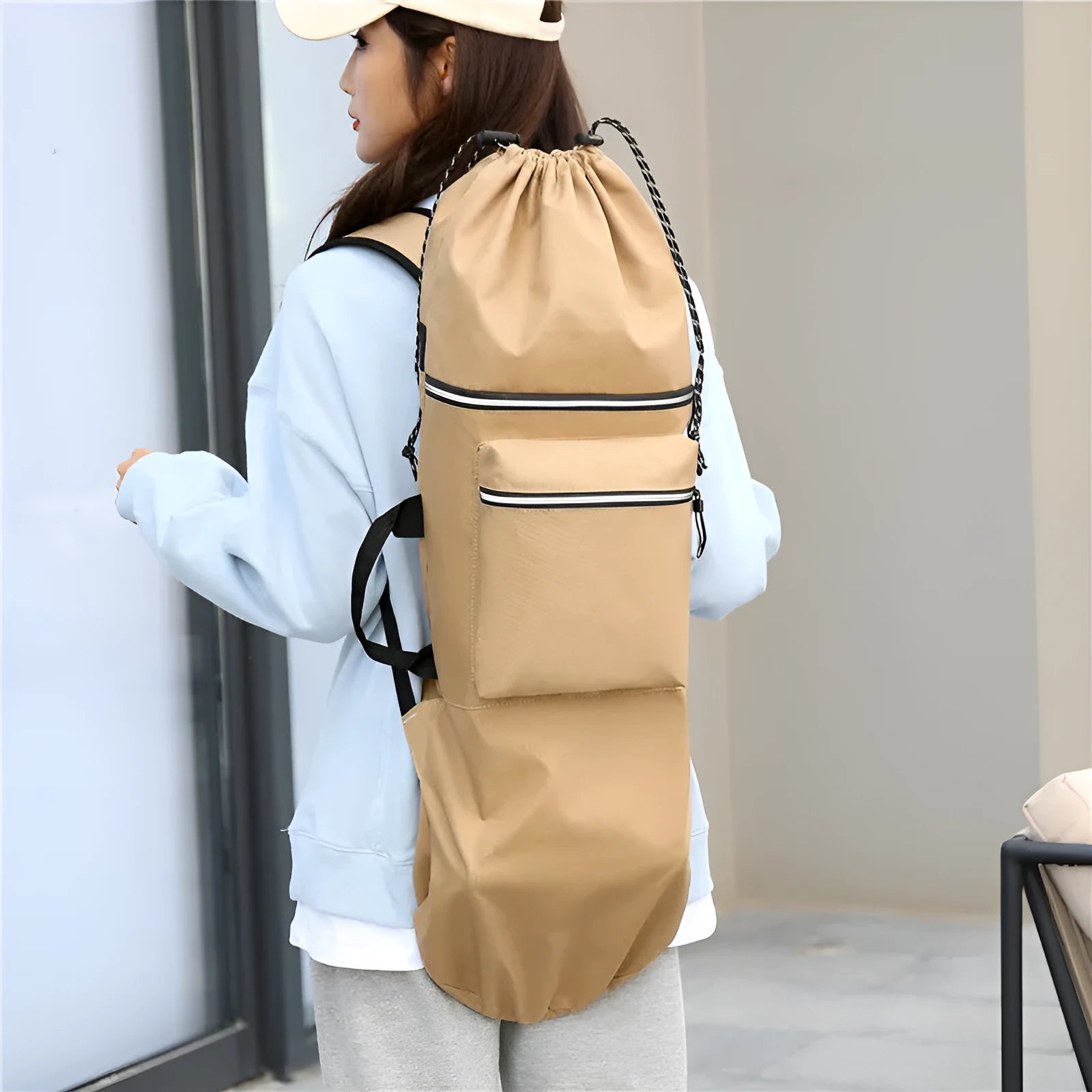 Roll-up skateboard bag in black nylon with an adjustable shoulder strap, shown carrying a skateboard.