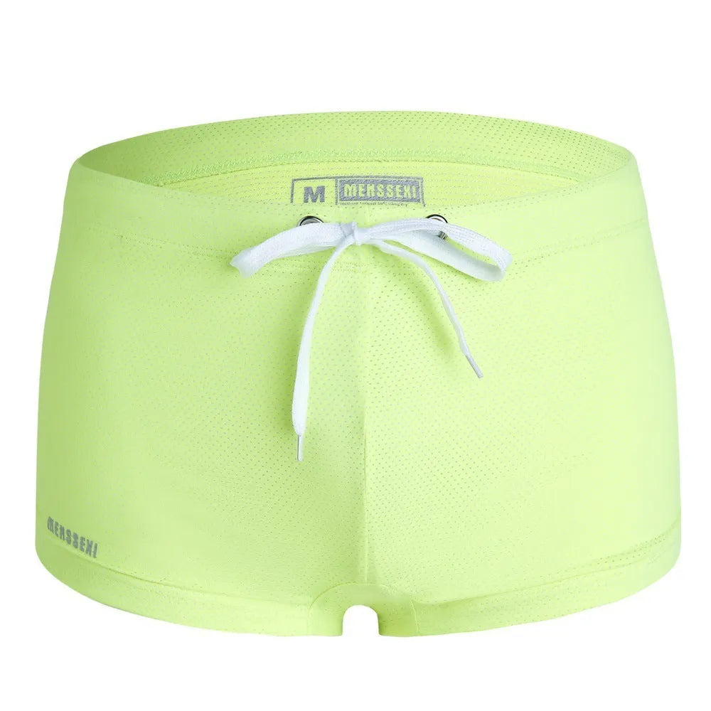 Men's solid colour low waist swimming trunks in nylon, shown in multiple colours including fluorescent green and black.