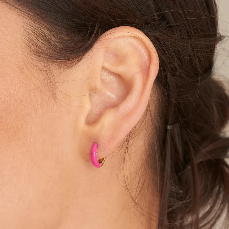 A pair of curved U-shaped drop earrings with a glossy light green oval and ring geometric design on copper wire.