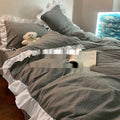 Four-piece washed cotton quilt cover set in a soft pastel colour, shown on a bed with matching pillowcases.