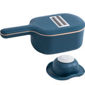 Dark blue scoop vegetable cutter with four stainless steel blades, hand guard and drain basket on a kitchen worktop
