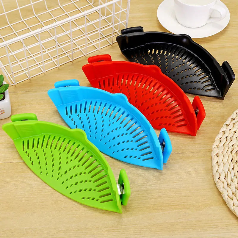 Silicone clip-on colander strainer in black with stainless steel clip attached to a pot rim for draining liquid