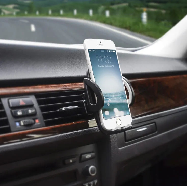 Black plastic car phone holder mounted on air conditioning outlet holding smartphone