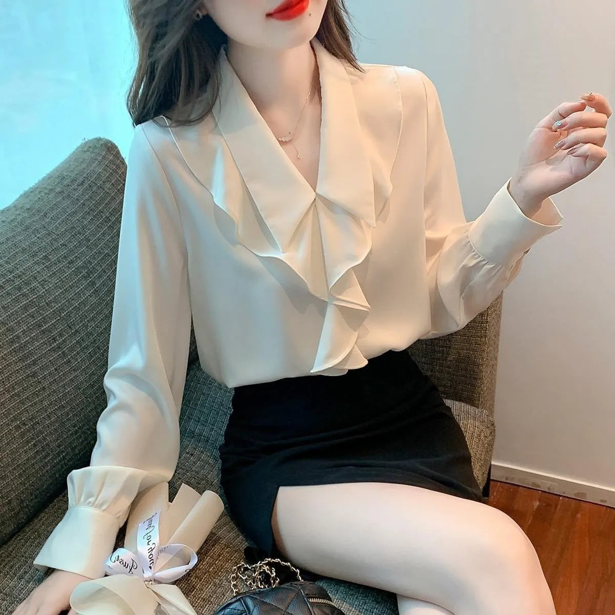 Ladies white chiffon blouse with long sleeves on a plain background