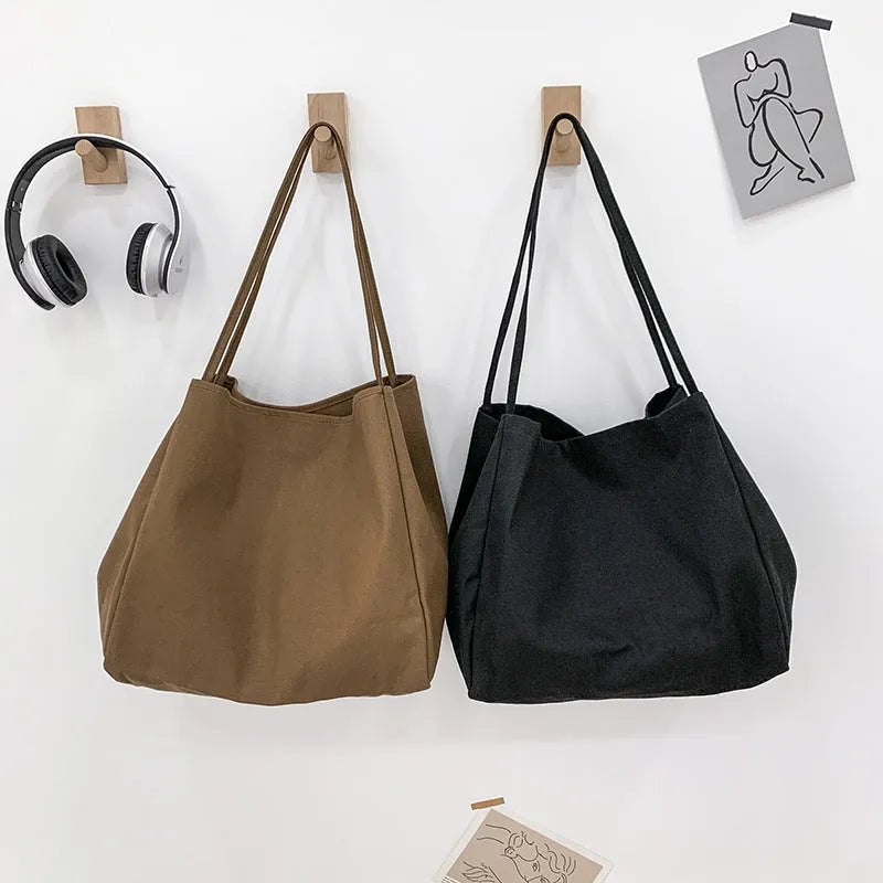 Women's solid colour canvas handbag showing horizontal square shape and double shoulder straps