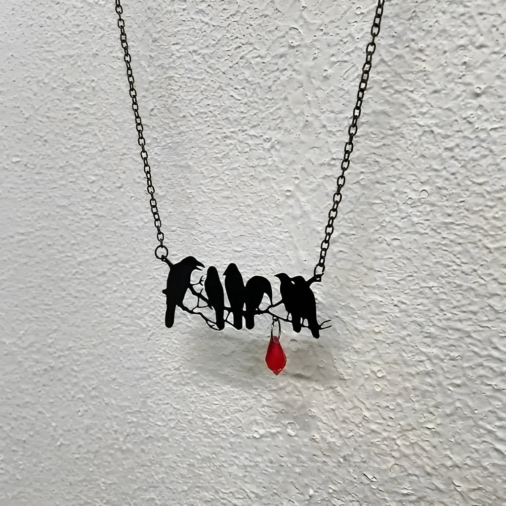 Black Gothic crow necklace with electroplated finish and cross chain on dark background