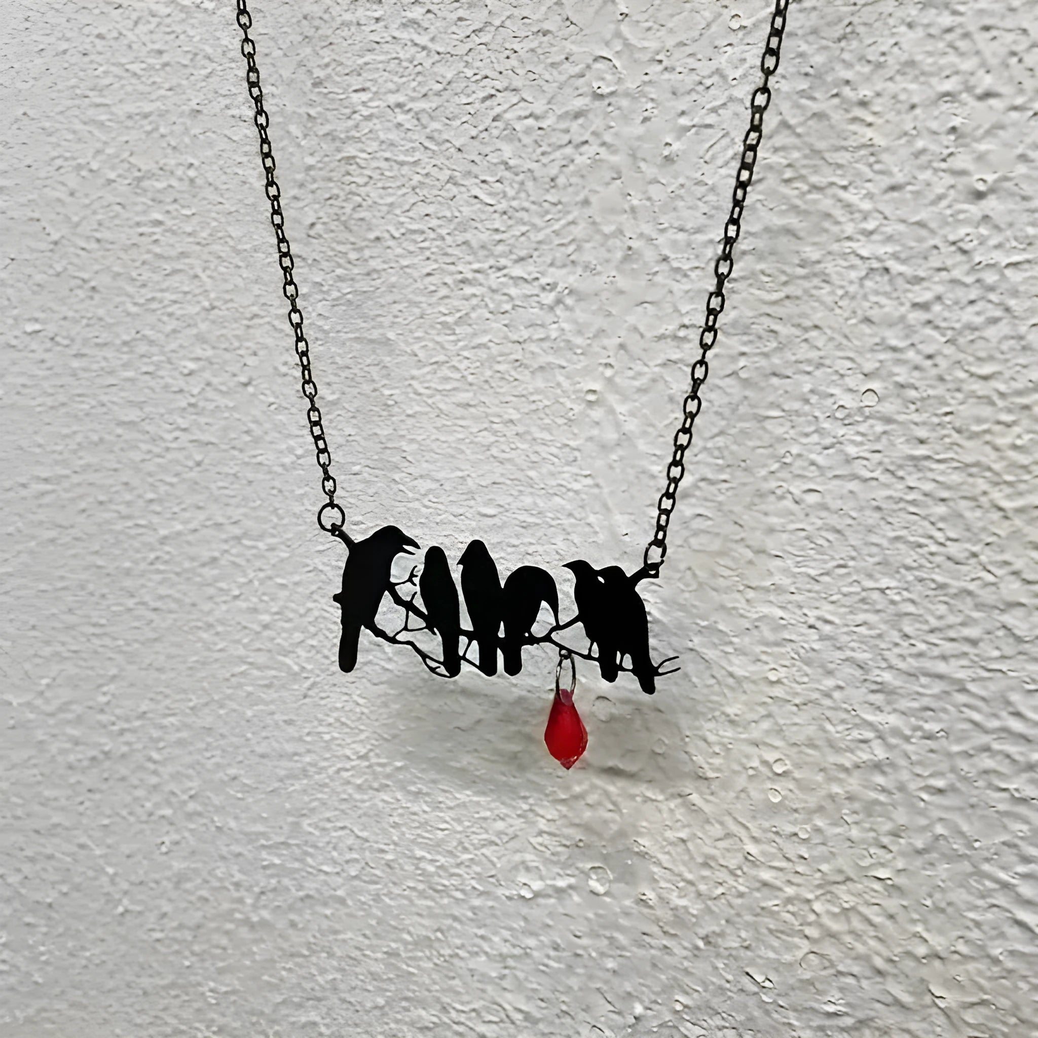 Black Gothic crow necklace with electroplated finish and cross chain on dark background