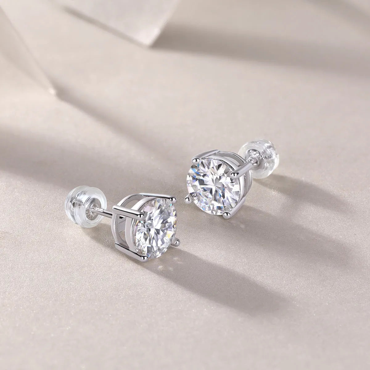 Pair of moissanite stud earrings with platinum-plated S925 silver settings, on a gift box, available in black or transparent stones