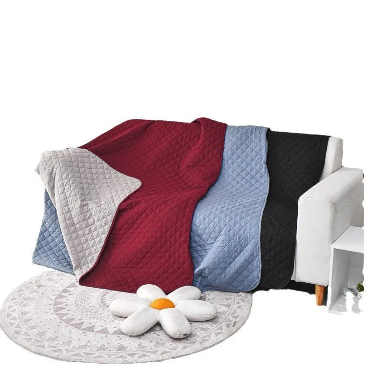 Reversible waterproof dog blanket laid on a sofa, showing two colour options.